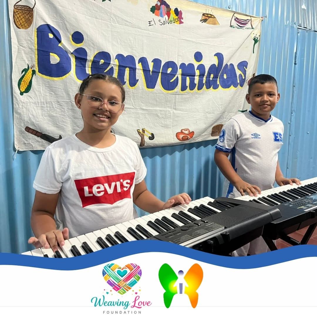 Young student smiling at a keyboard in front of a painted wall