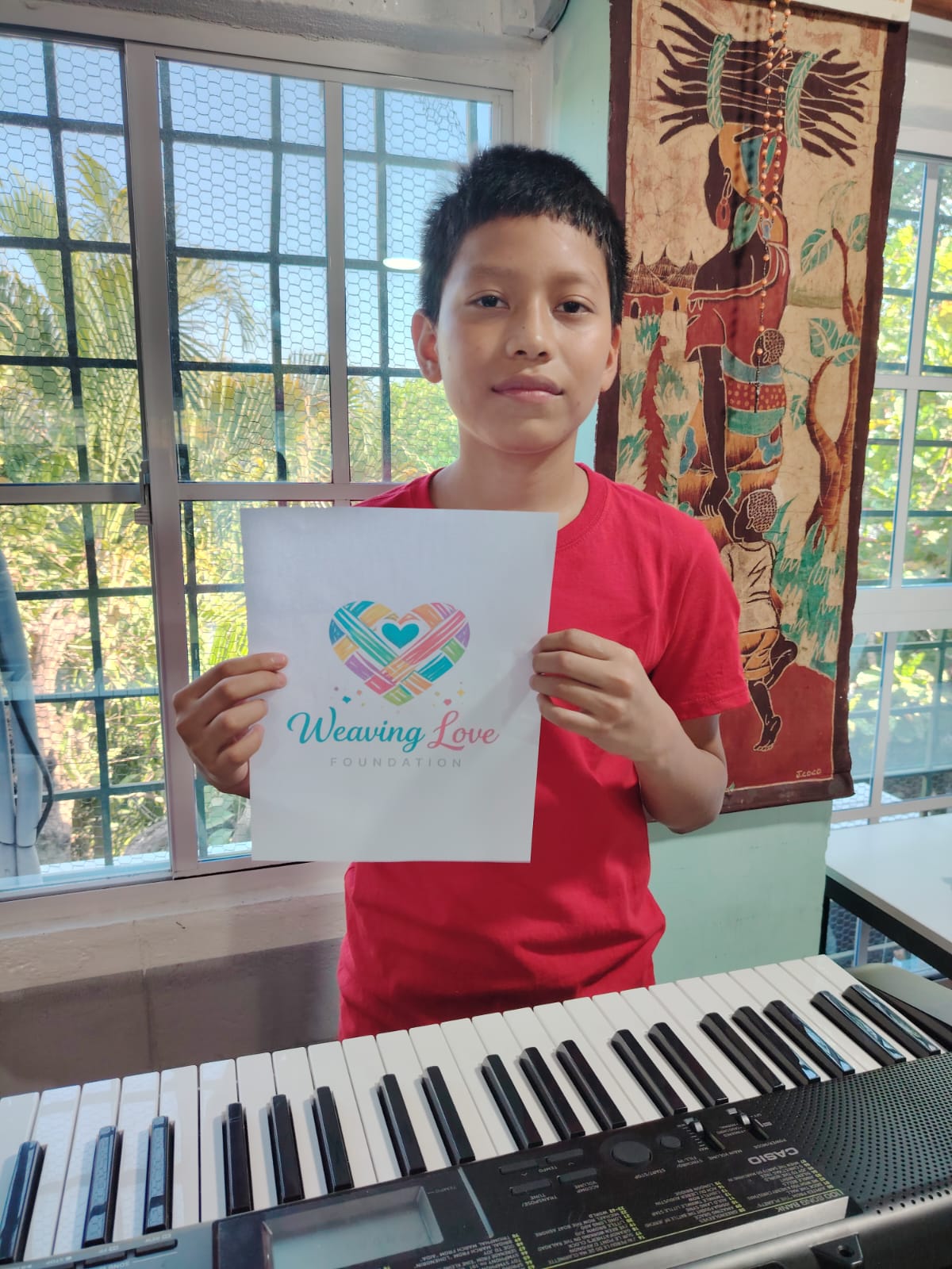 Girl holding a Weaving Love Foundation page by a keyboard
